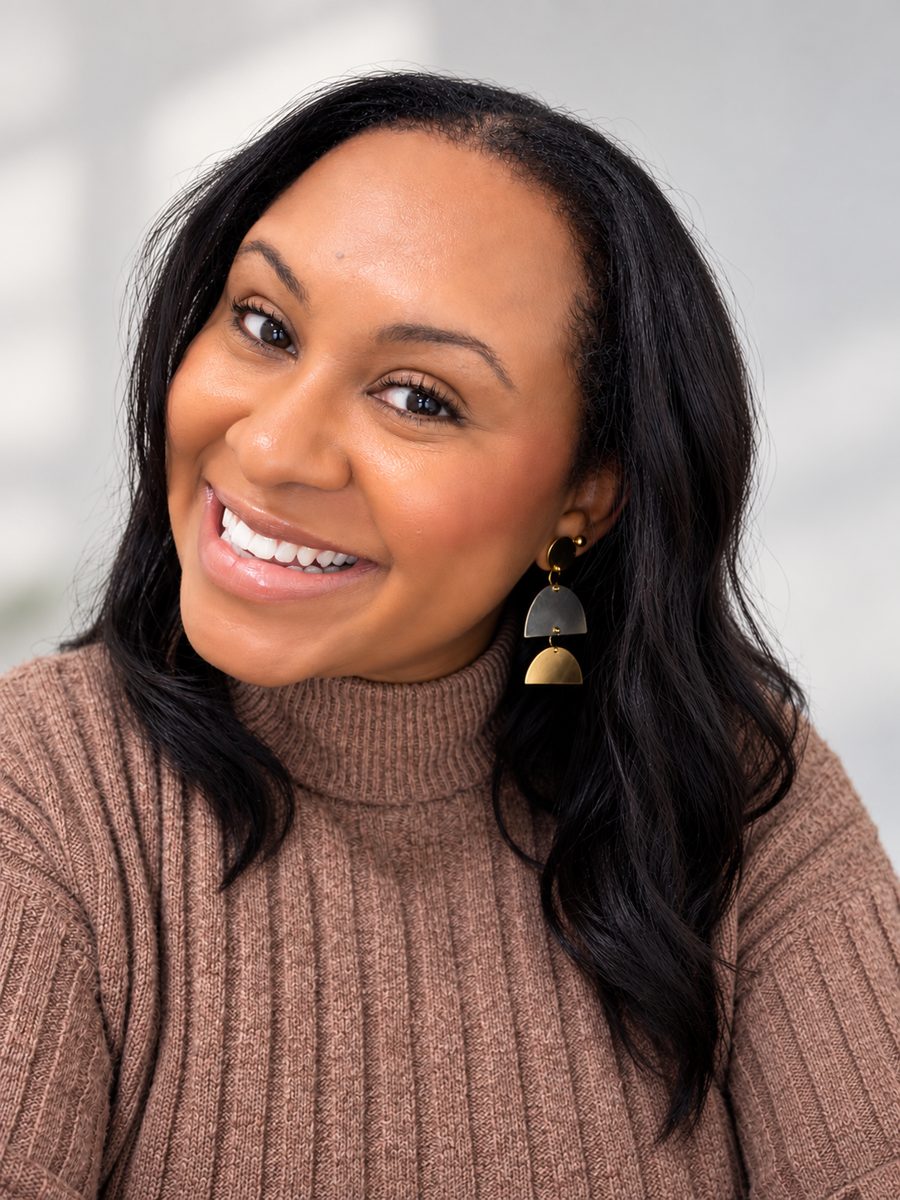 Portrait of Fleurztael smiling, head tilted, wearing gold geometric earrings and a mocha turtleneck